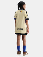 Child wearing a beige sports jersey with visible branding on a white background