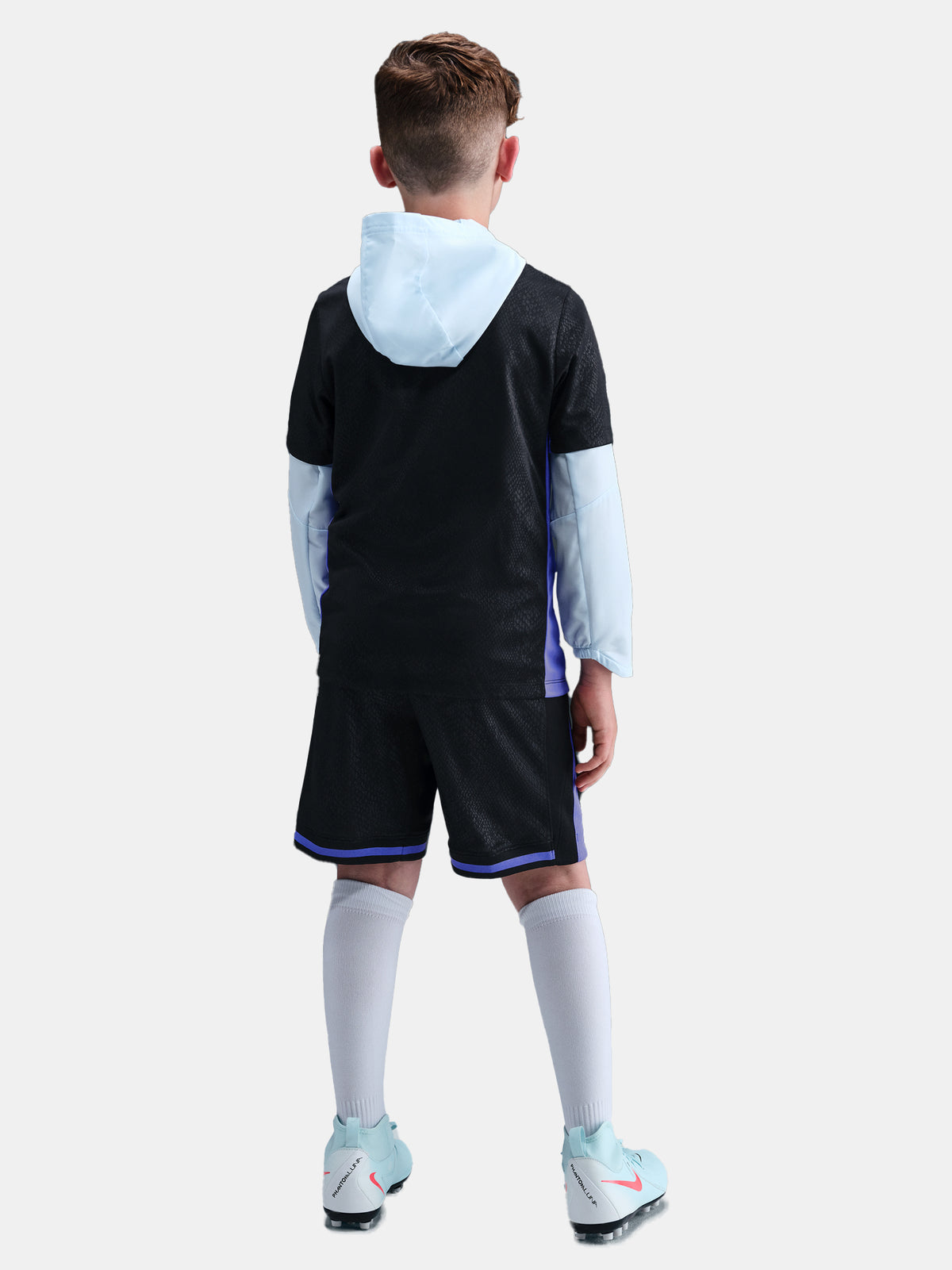 Person wearing a black sports outfit with white socks and shoes on a light gray background