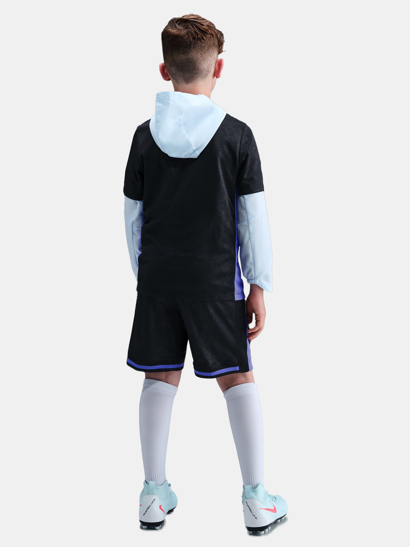 Person wearing a black sports outfit with white socks and shoes on a light gray background