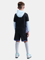 Person wearing a black sports outfit with white socks and shoes on a light gray background