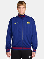 FC Barcelona 2025/26 retro-inspired track jacket featuring a royal blue base with fine vertical pinstripes, yellow Nike swoosh, and the club crest on the chest. Ribbed cuffs and hem include red and navy stripe details for a vintage finish.
