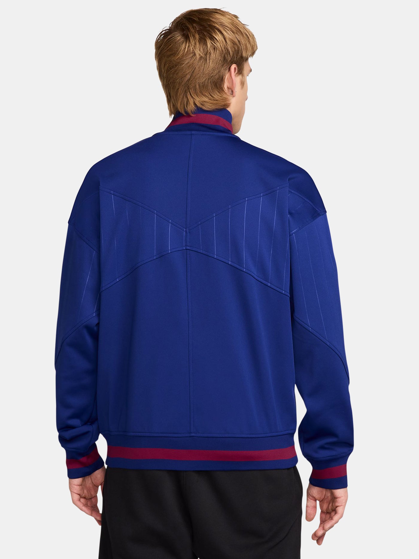FC Barcelona 2025/26 retro-inspired track jacket featuring a royal blue base with fine vertical pinstripes, yellow Nike swoosh, and the club crest on the chest. Ribbed cuffs and hem include red and navy stripe details for a vintage finish.
