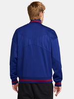 FC Barcelona 2025/26 retro-inspired track jacket featuring a royal blue base with fine vertical pinstripes, yellow Nike swoosh, and the club crest on the chest. Ribbed cuffs and hem include red and navy stripe details for a vintage finish.
