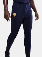 FC Barcelona tapered training pants in navy blue. Designed for performance and comfort with a slim fit, featuring the club crest and a yellow Nike swoosh on the front. Ideal for training sessions or casual wear.
