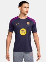 FC Barcelona navy training shirt with purple shoulder accents, yellow Nike logo, club crest, and Spotify sponsor, paired with gray shorts featuring a coral Nike logo.