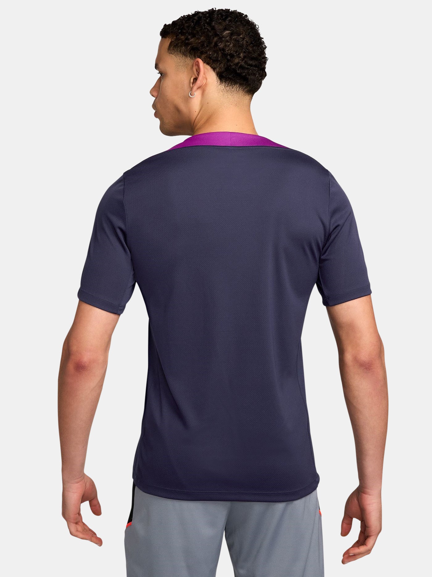 FC Barcelona navy training shirt with purple shoulder accents, yellow Nike logo, club crest, and Spotify sponsor, paired with gray shorts featuring a coral Nike logo.