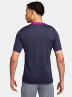FC Barcelona navy training shirt with purple shoulder accents, yellow Nike logo, club crest, and Spotify sponsor, paired with gray shorts featuring a coral Nike logo.