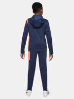 Kid wearing a navy blue FC Barcelona Nike tracksuit with coral details, featuring the club crest and Nike swoosh on the jacket.