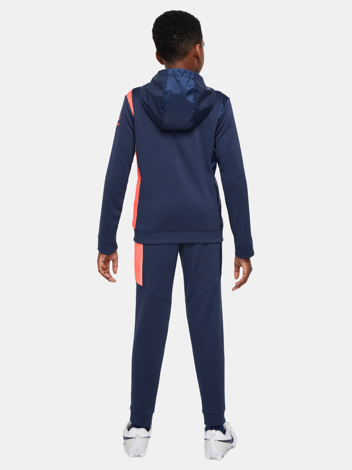 Kid wearing a navy blue FC Barcelona Nike tracksuit with coral details, featuring the club crest and Nike swoosh on the jacket.