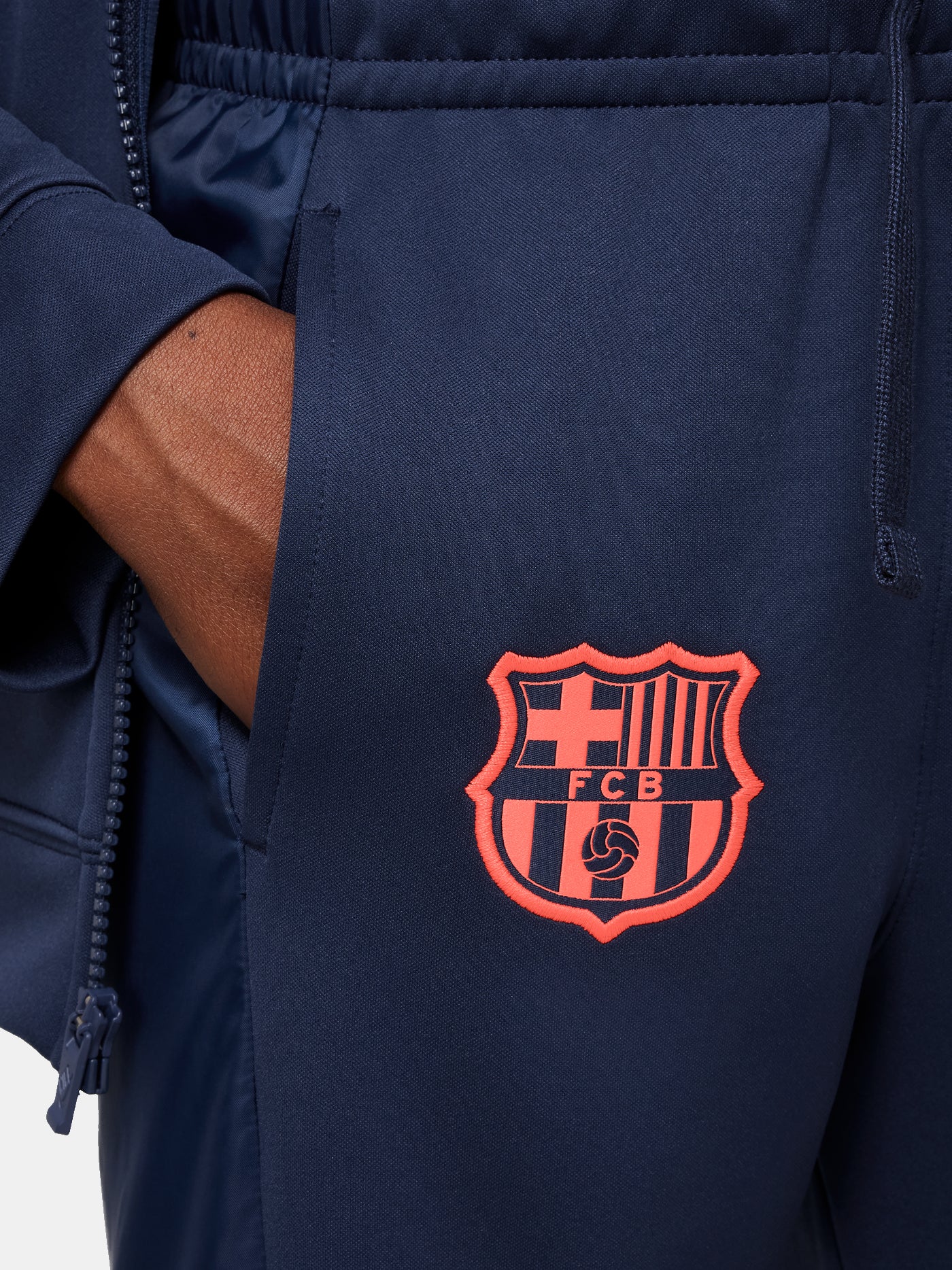Kid wearing a navy blue FC Barcelona Nike tracksuit with coral details, featuring the club crest and Nike swoosh on the jacket.