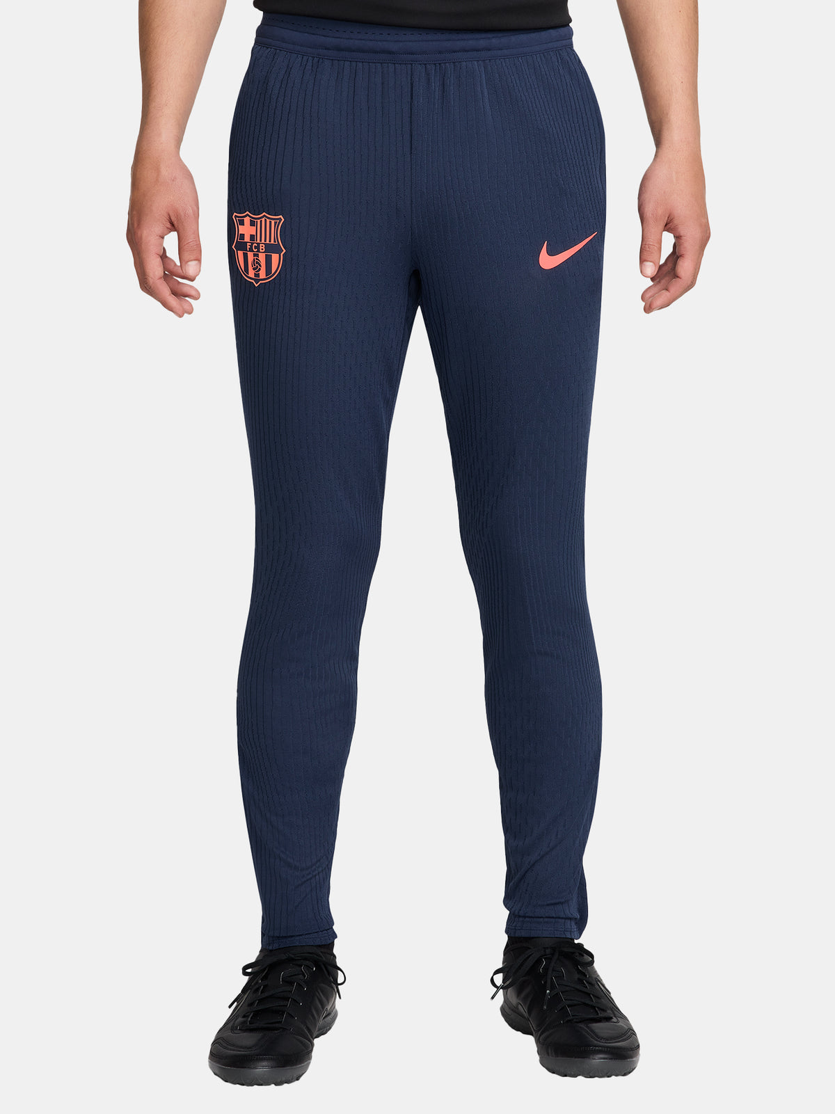FC Barcelona navy blue training pants with slim fit, featuring the club crest and Nike logo in coral on the front