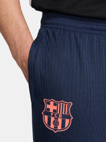 FC Barcelona navy blue training pants with slim fit, featuring the club crest and Nike logo in coral on the front