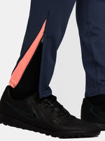 FC Barcelona navy blue training pants with slim fit, featuring the club crest and Nike logo in coral on the front