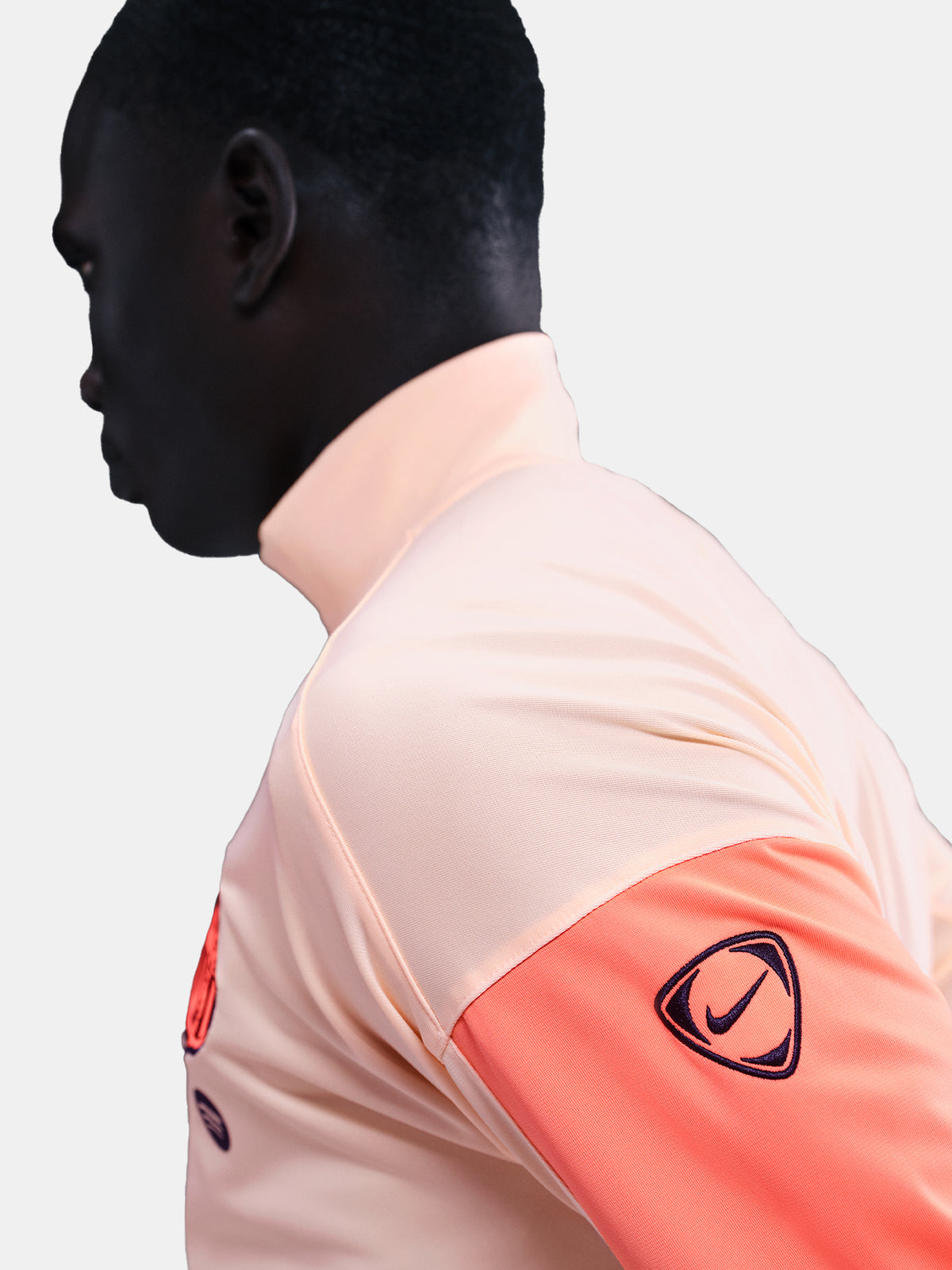 FC Barcelona Nike jacket with coral sleeve detail, paired with navy jogger pants featuring the club crest and Nike swoosh