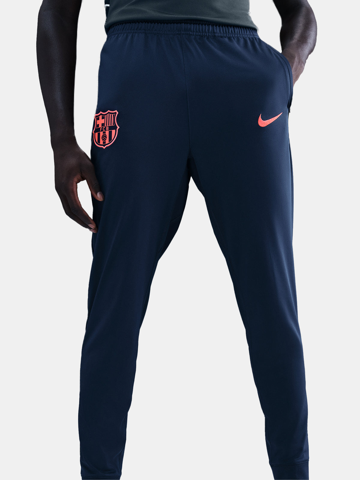 FC Barcelona Nike jacket with coral sleeve detail, paired with navy jogger pants featuring the club crest and Nike swoosh