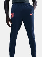 FC Barcelona Nike jacket with coral sleeve detail, paired with navy jogger pants featuring the club crest and Nike swoosh