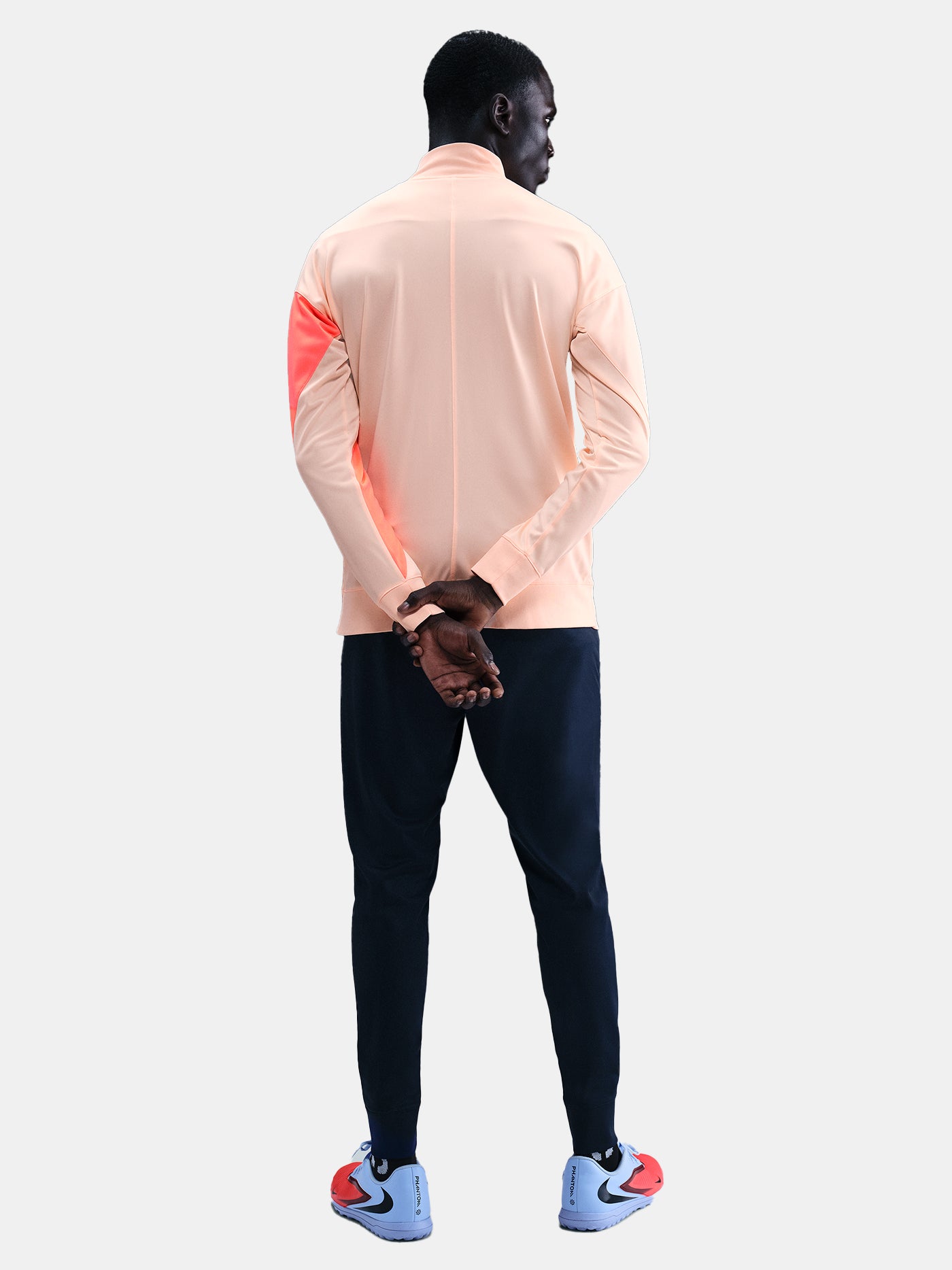 FC Barcelona Nike jacket with coral sleeve detail, paired with navy jogger pants featuring the club crest and Nike swoosh