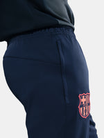 FC Barcelona Nike jacket with coral sleeve detail, paired with navy jogger pants featuring the club crest and Nike swoosh