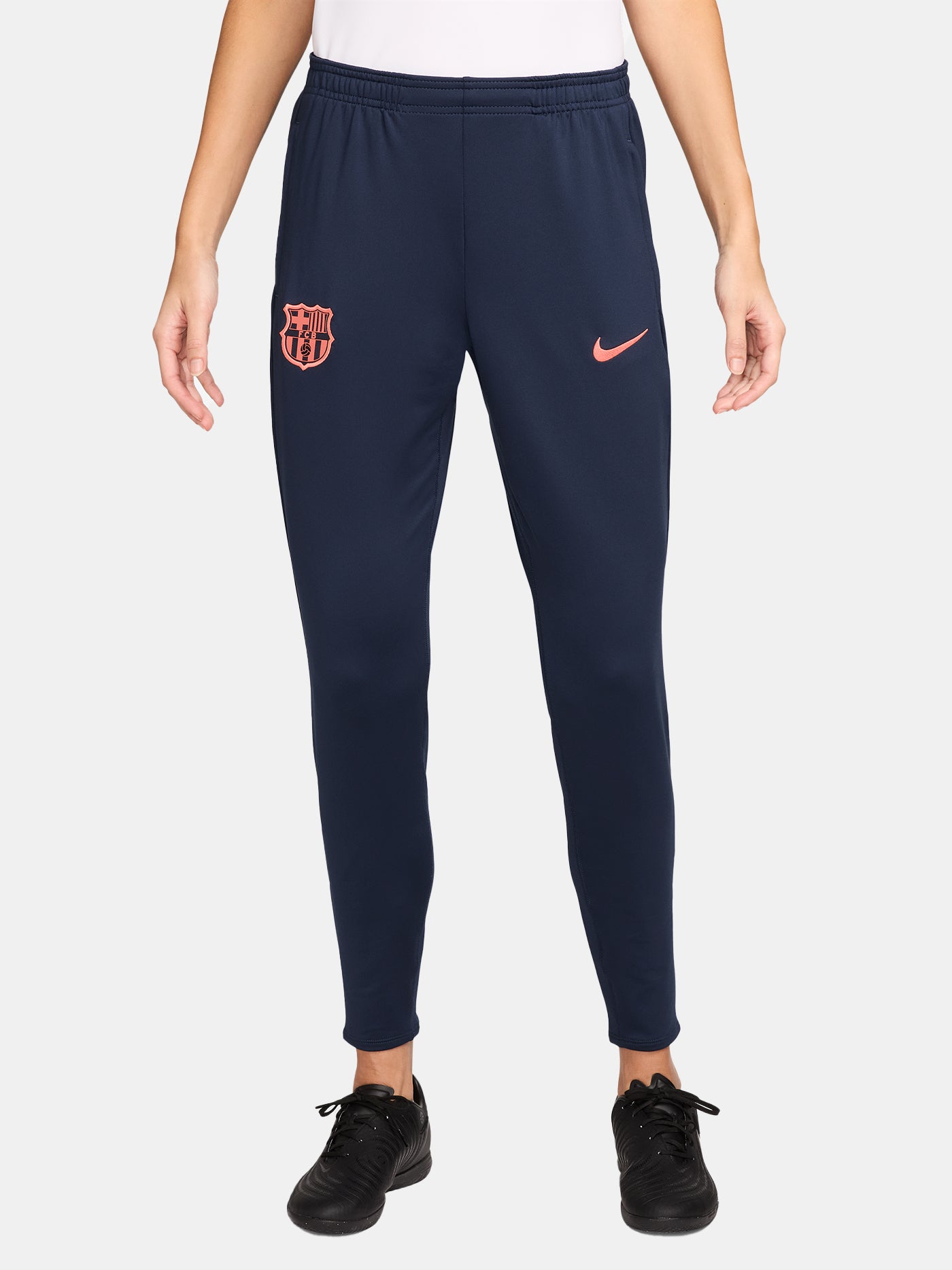 FC Barcelona navy blue training pants with slim fit, featuring the club crest and Nike logo in coral on the front