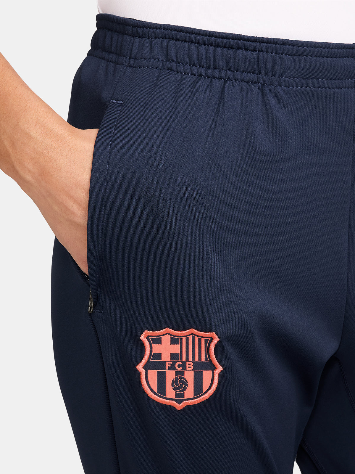 FC Barcelona navy blue training pants with slim fit, featuring the club crest and Nike logo in coral on the front