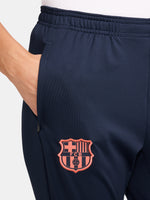 FC Barcelona navy blue training pants with slim fit, featuring the club crest and Nike logo in coral on the front