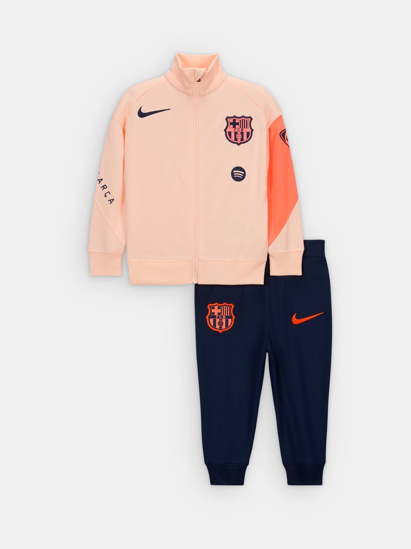 FC Barcelona Nike jacket with coral sleeve detail, paired with navy jogger pants featuring the club crest and Nike swoosh