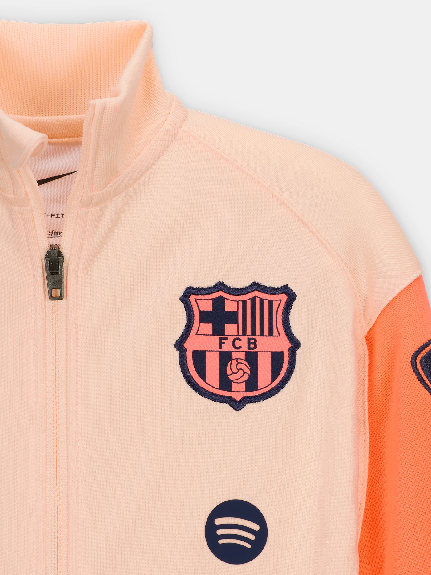 FC Barcelona Nike jacket with coral sleeve detail, paired with navy jogger pants featuring the club crest and Nike swoosh