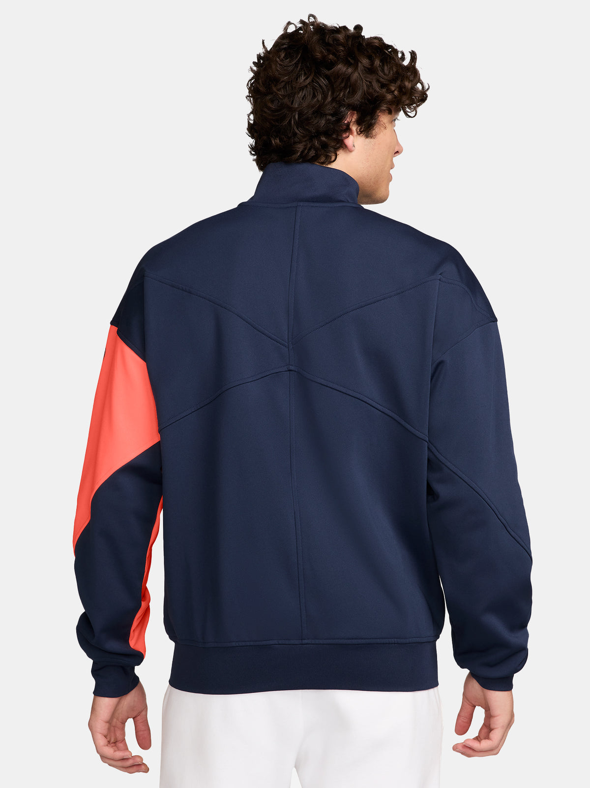 FC Barcelona navy blue jacket with coral details, including a coral sleeve, zipper, Nike logo, and club crest, paired with white Nike pants.