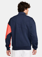 FC Barcelona navy blue jacket with coral details, including a coral sleeve, zipper, Nike logo, and club crest, paired with white Nike pants.