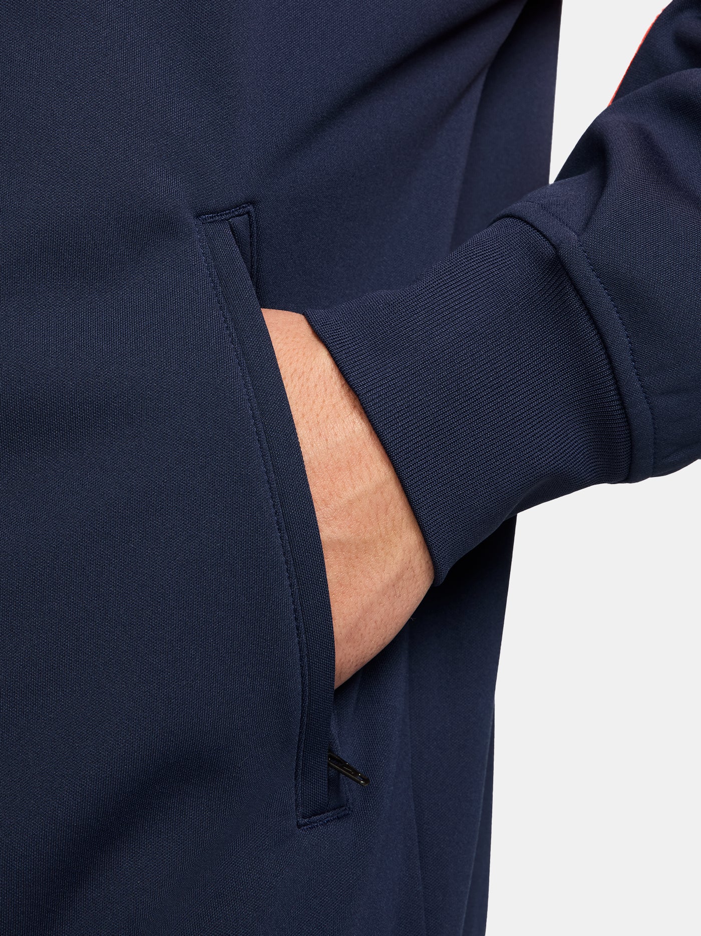 FC Barcelona navy blue jacket with coral details, including a coral sleeve, zipper, Nike logo, and club crest, paired with white Nike pants.