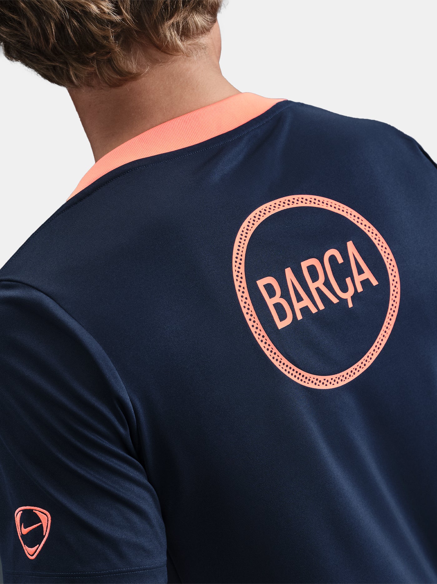 FC Barcelona navy training shirt with coral Nike logo, Spotify sponsor, and geometric coral and white pattern design on the shoulder and chest