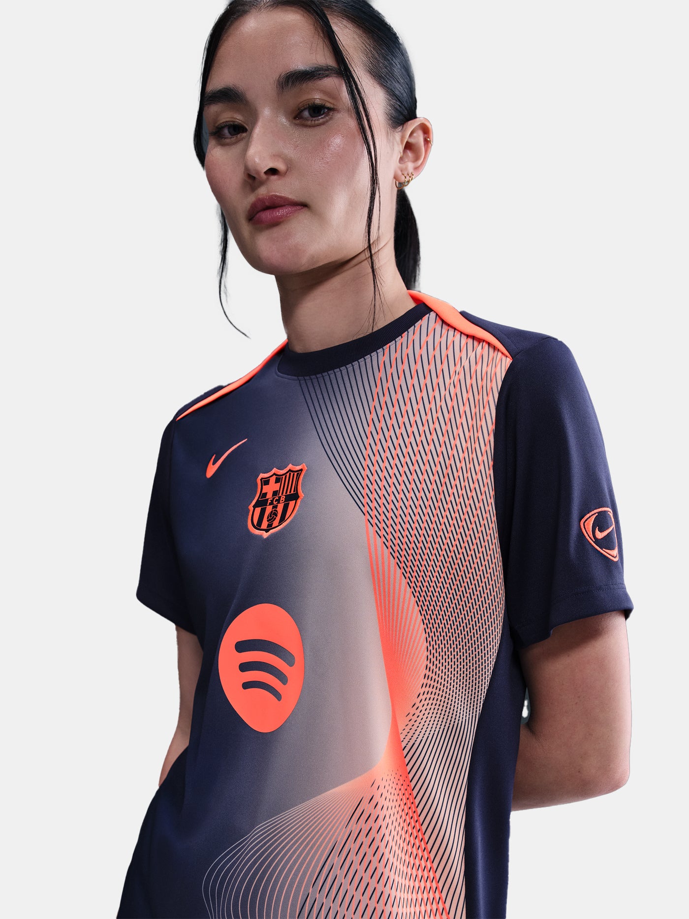 FC Barcelona navy training shirt with coral Nike logo, Spotify sponsor, and geometric coral and white pattern design on the shoulder and chest