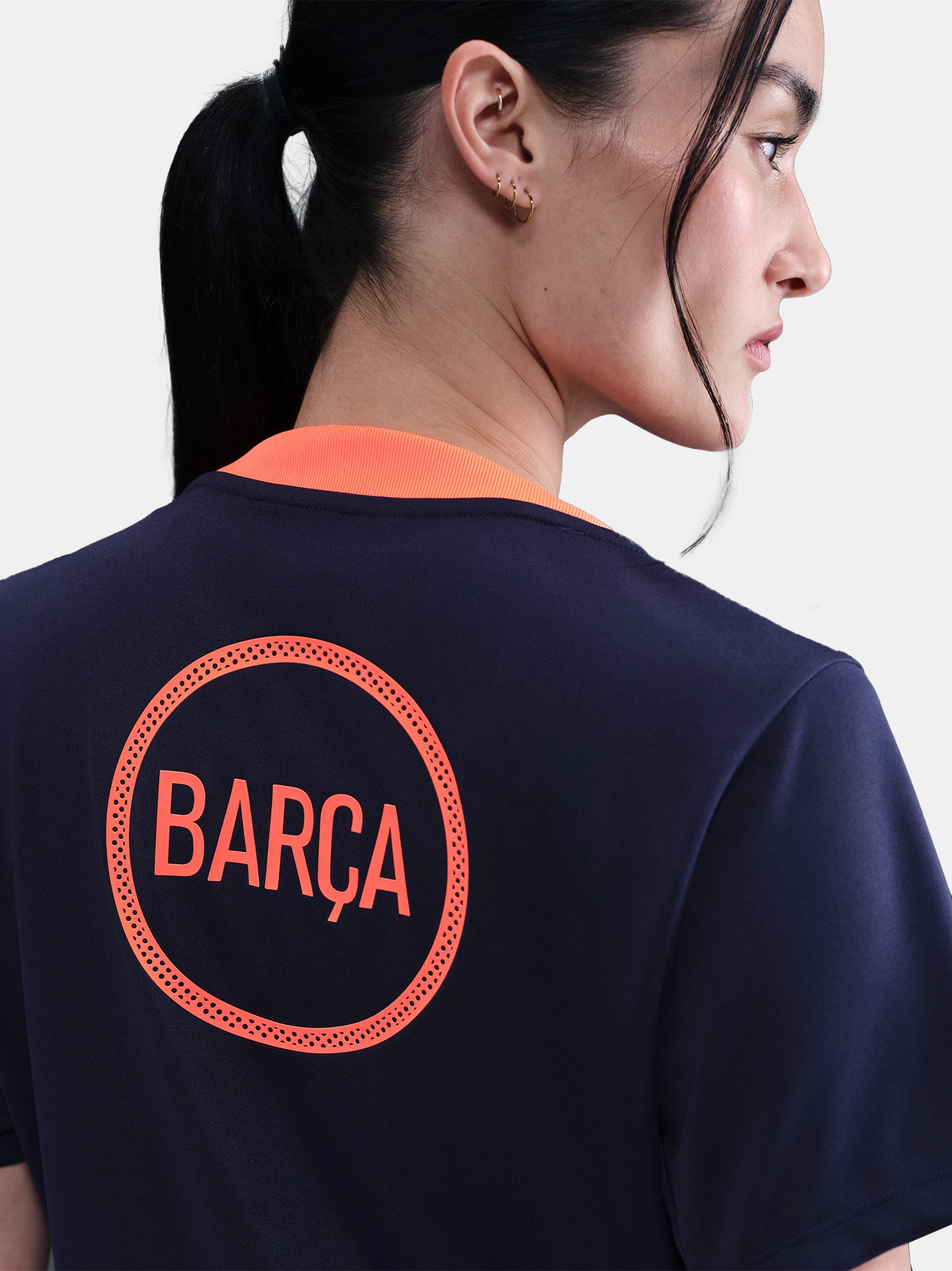 FC Barcelona navy training shirt with coral Nike logo, Spotify sponsor, and geometric coral and white pattern design on the shoulder and chest