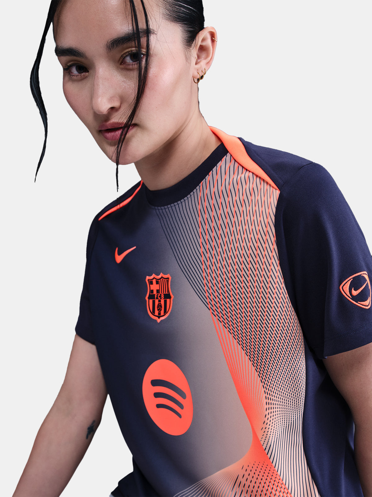 FC Barcelona navy training shirt with coral Nike logo, Spotify sponsor, and geometric coral and white pattern design on the shoulder and chest