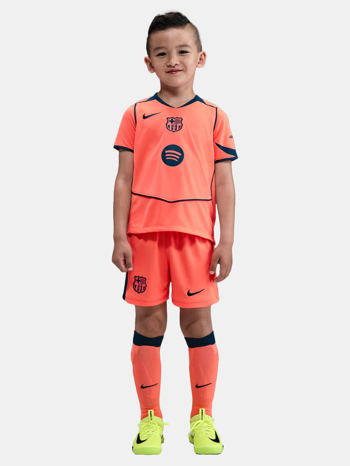 FC Barcelona 2025/26 third kit for kids in orange with navy blue details, including shirt, shorts, and socks.