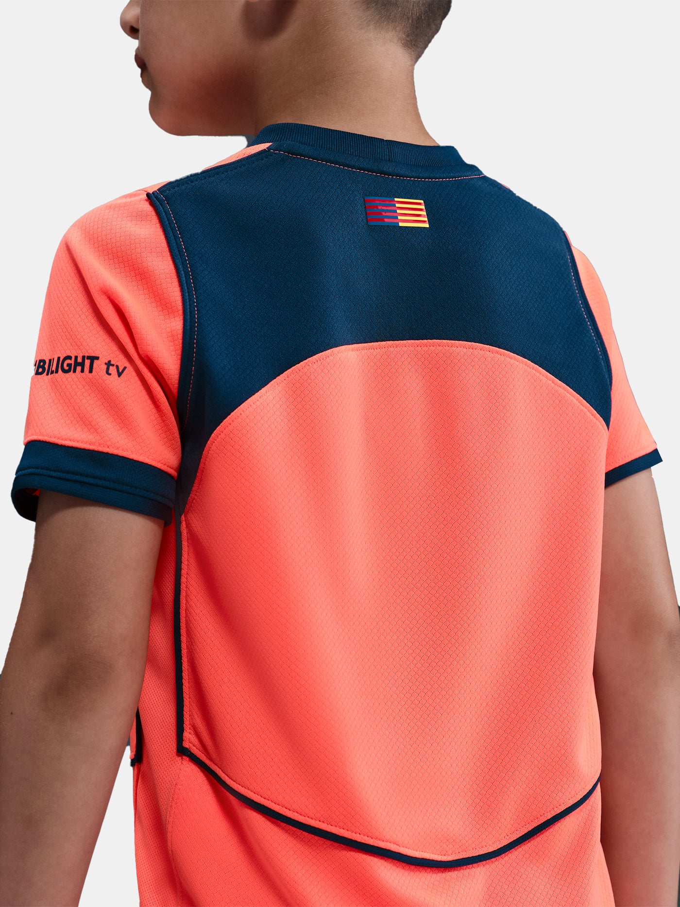 FC Barcelona 2025/26 third kit for kids in orange with navy blue details, including shirt, shorts, and socks.