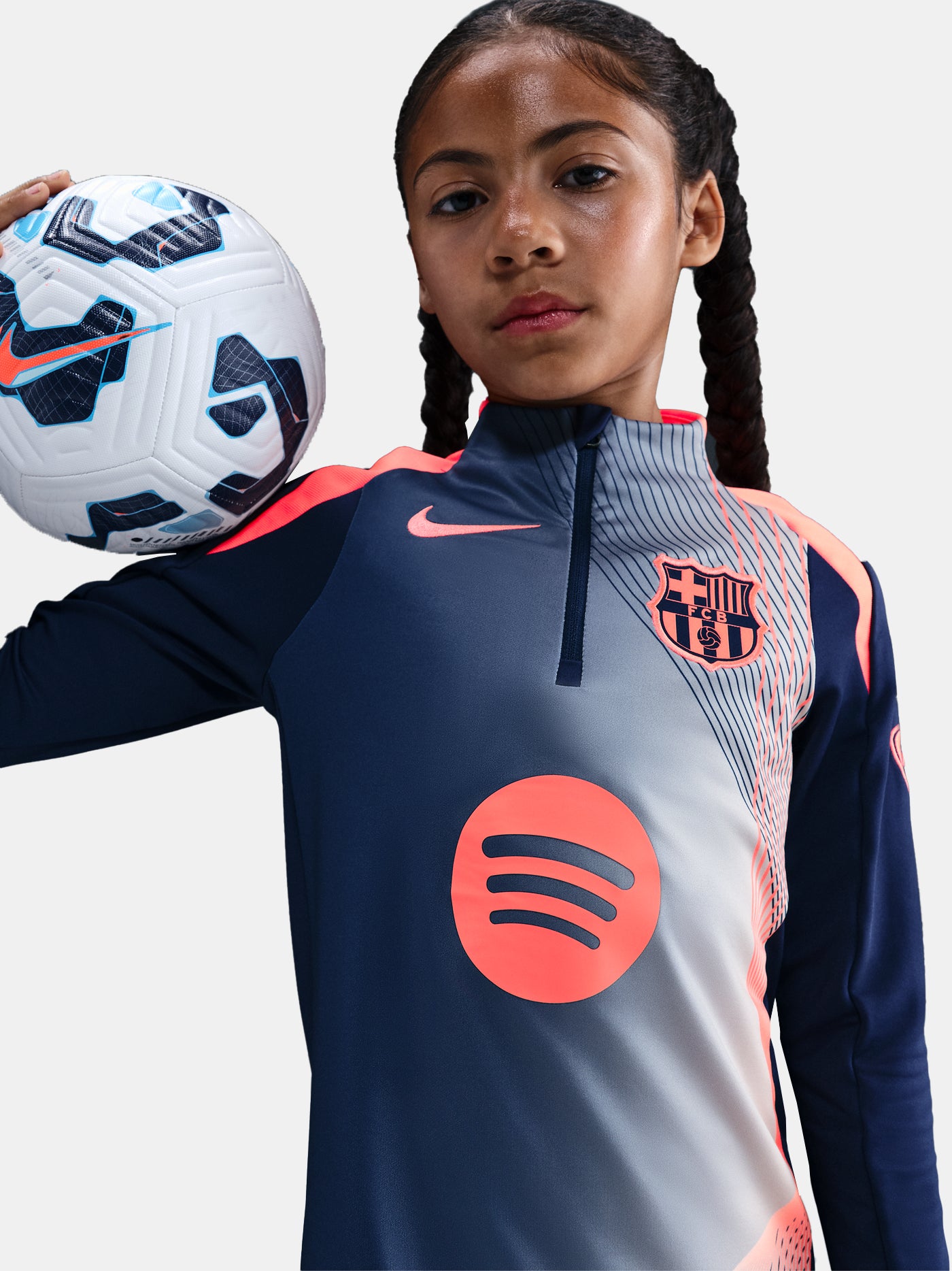 FC Barcelona navy training kit consisting of a long-sleeve top with coral Nike logo, Spotify sponsor and geometric design, paired with matching navy shorts featuring coral accents and the club crest.