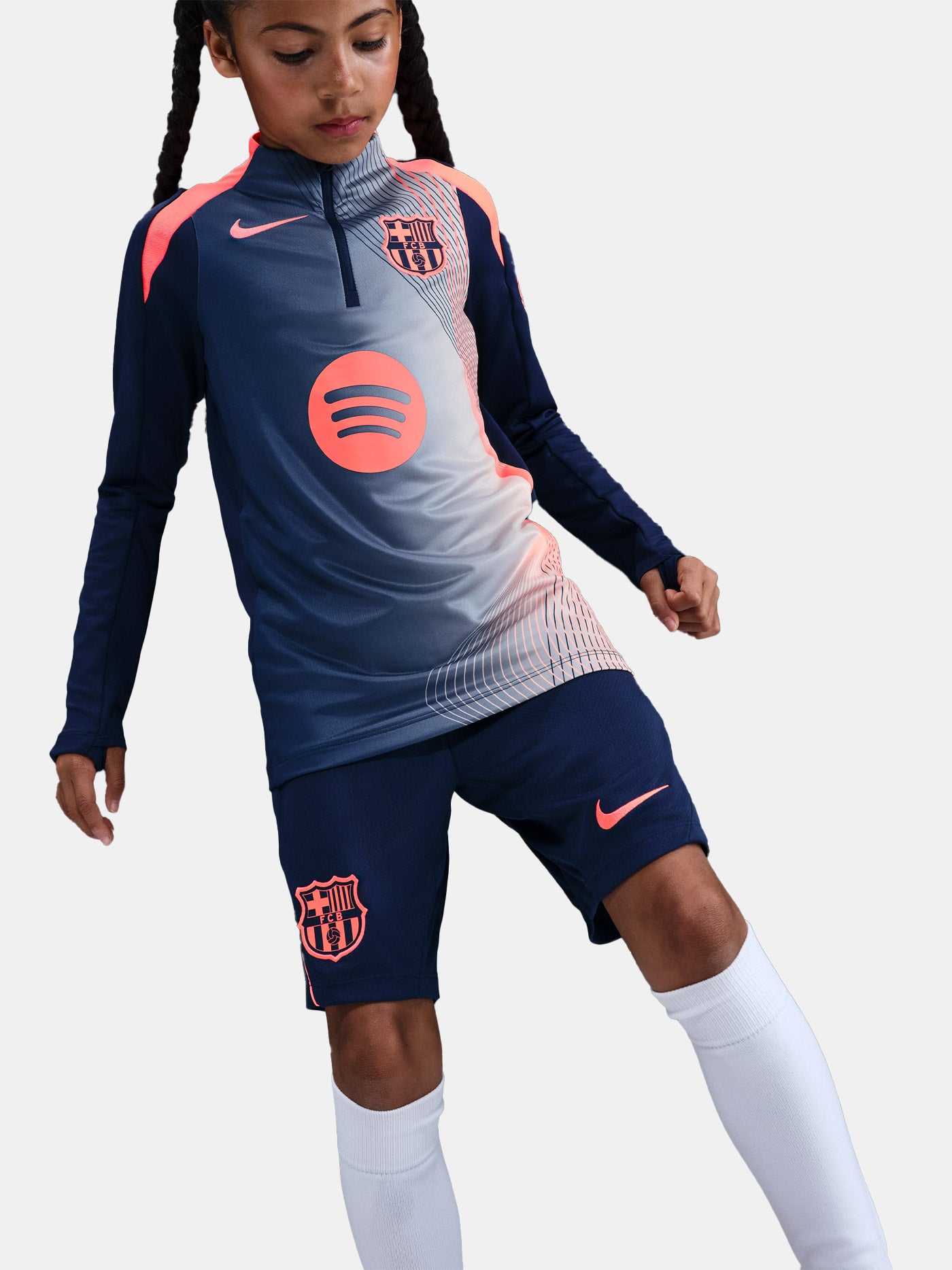 FC Barcelona navy training kit consisting of a long-sleeve top with coral Nike logo, Spotify sponsor and geometric design, paired with matching navy shorts featuring coral accents and the club crest.