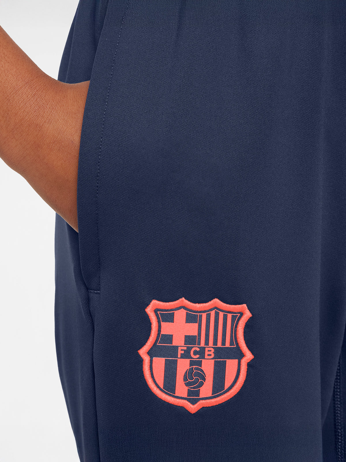 FC Barcelona navy blue training pants with slim fit, featuring the club crest and Nike logo in coral on the front
