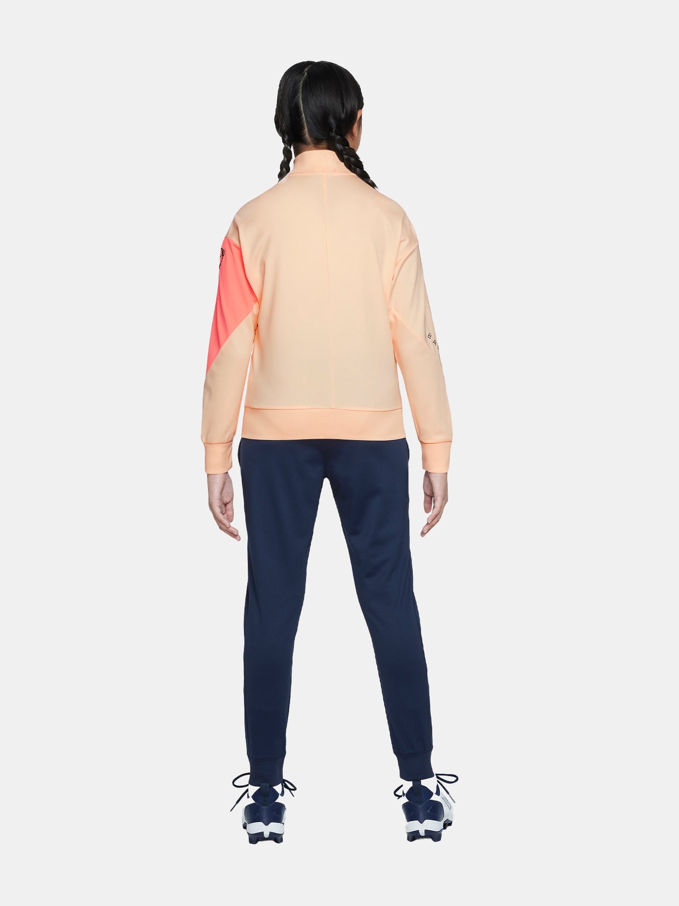 FC Barcelona Nike jacket with coral sleeve detail, paired with navy jogger pants featuring the club crest and Nike swoosh