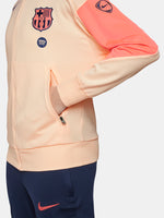 FC Barcelona Nike jacket with coral sleeve detail, paired with navy jogger pants featuring the club crest and Nike swoosh