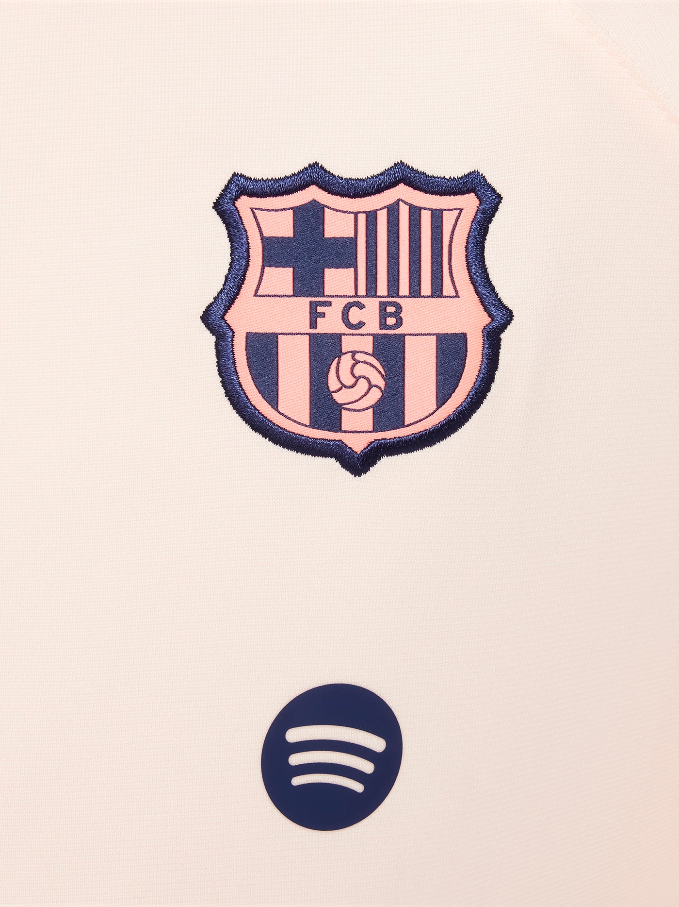 Child wearing a peach and orange FC Barcelona Nike jacket with navy blue pants, both featuring the club crest and Nike swoosh