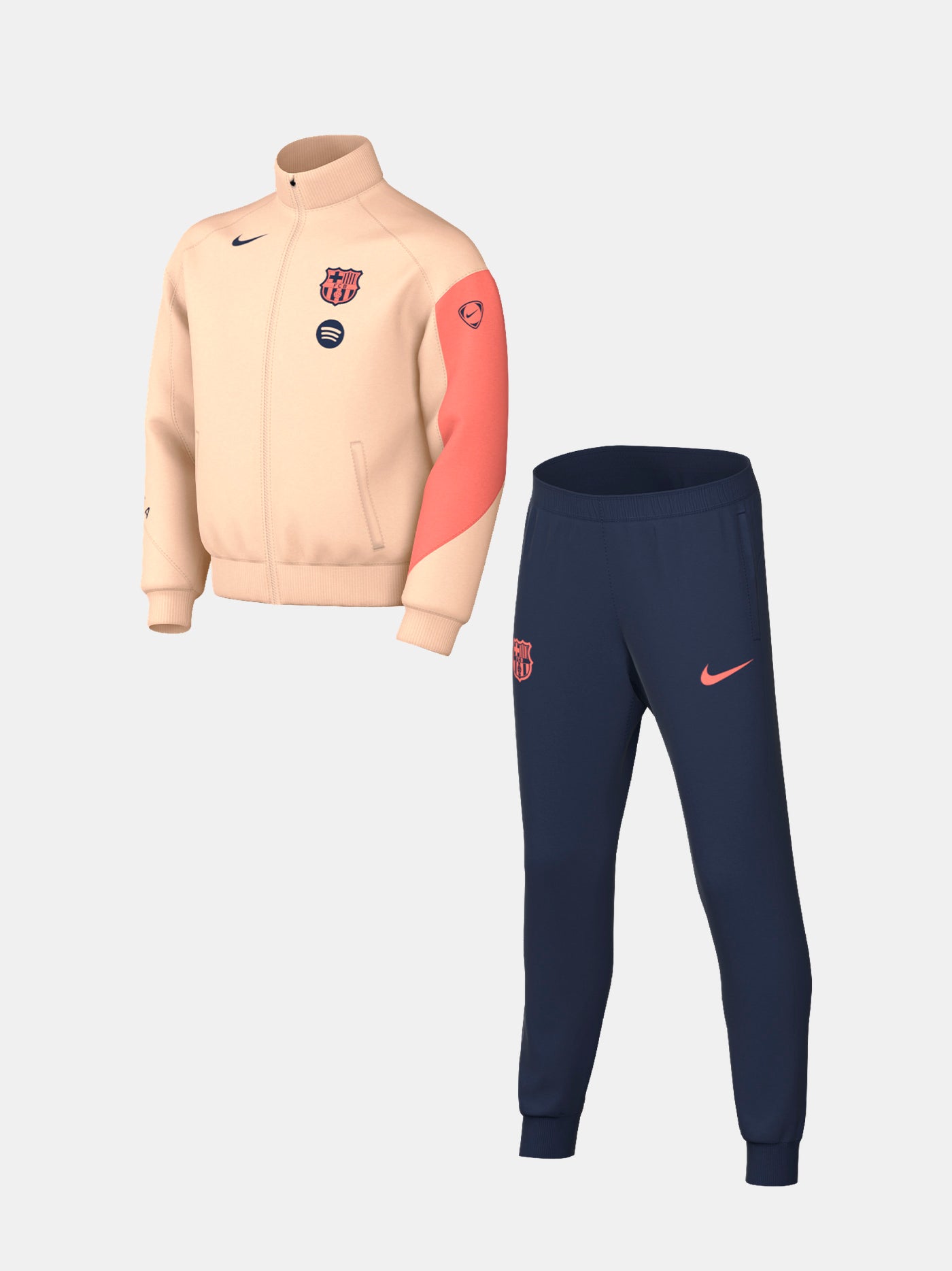 Child wearing a peach and orange FC Barcelona Nike jacket with navy blue pants, both featuring the club crest and Nike swoosh