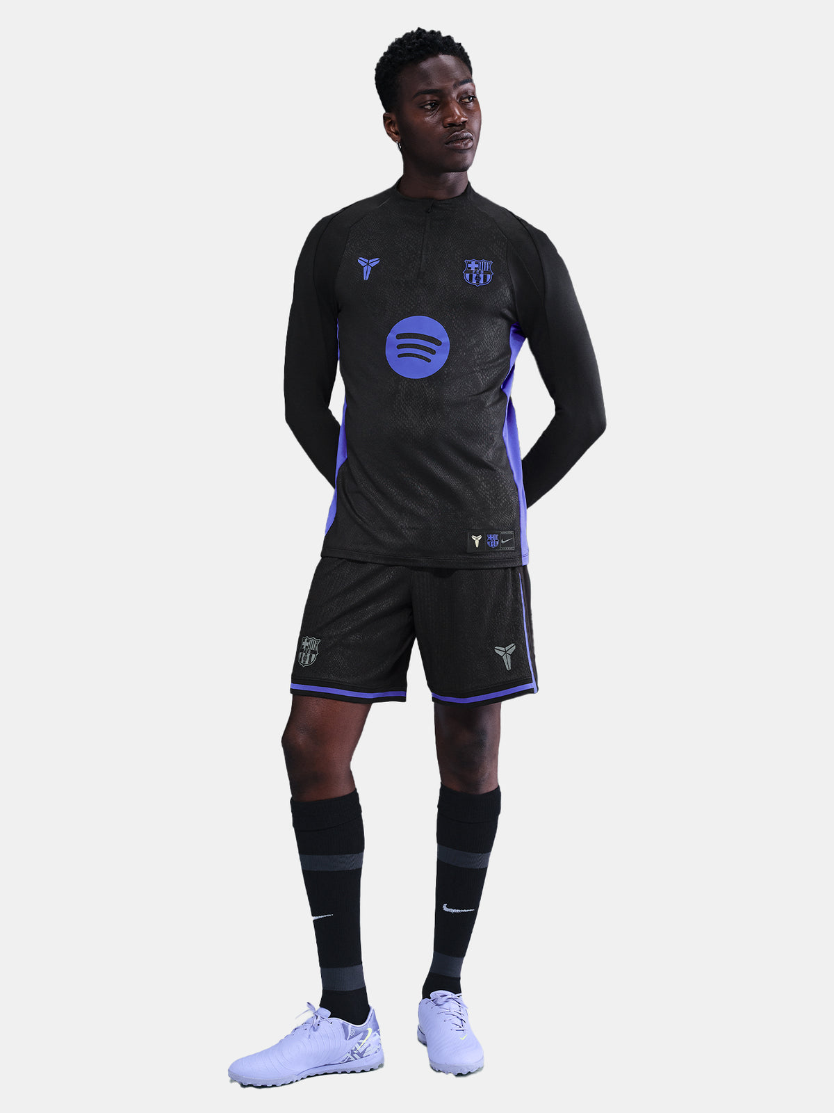 Black FC Barcelona training top with purple details, including the club crest, Nike logo, and Spotify sponsor logo, worn by a person.