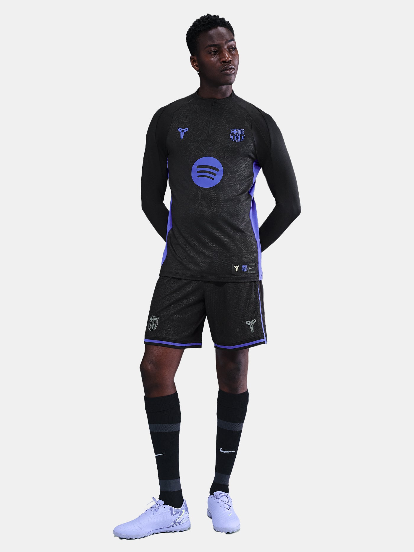 Black FC Barcelona training top with purple details, including the club crest, Nike logo, and Spotify sponsor logo, worn by a person.