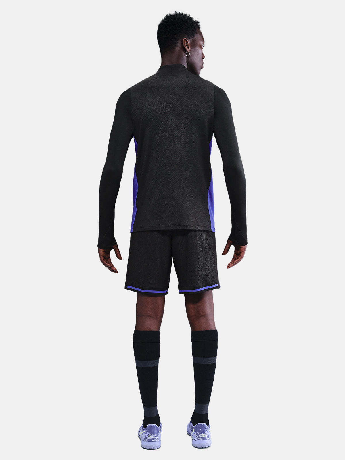 Black FC Barcelona training top with purple details, including the club crest, Nike logo, and Spotify sponsor logo, worn by a person.