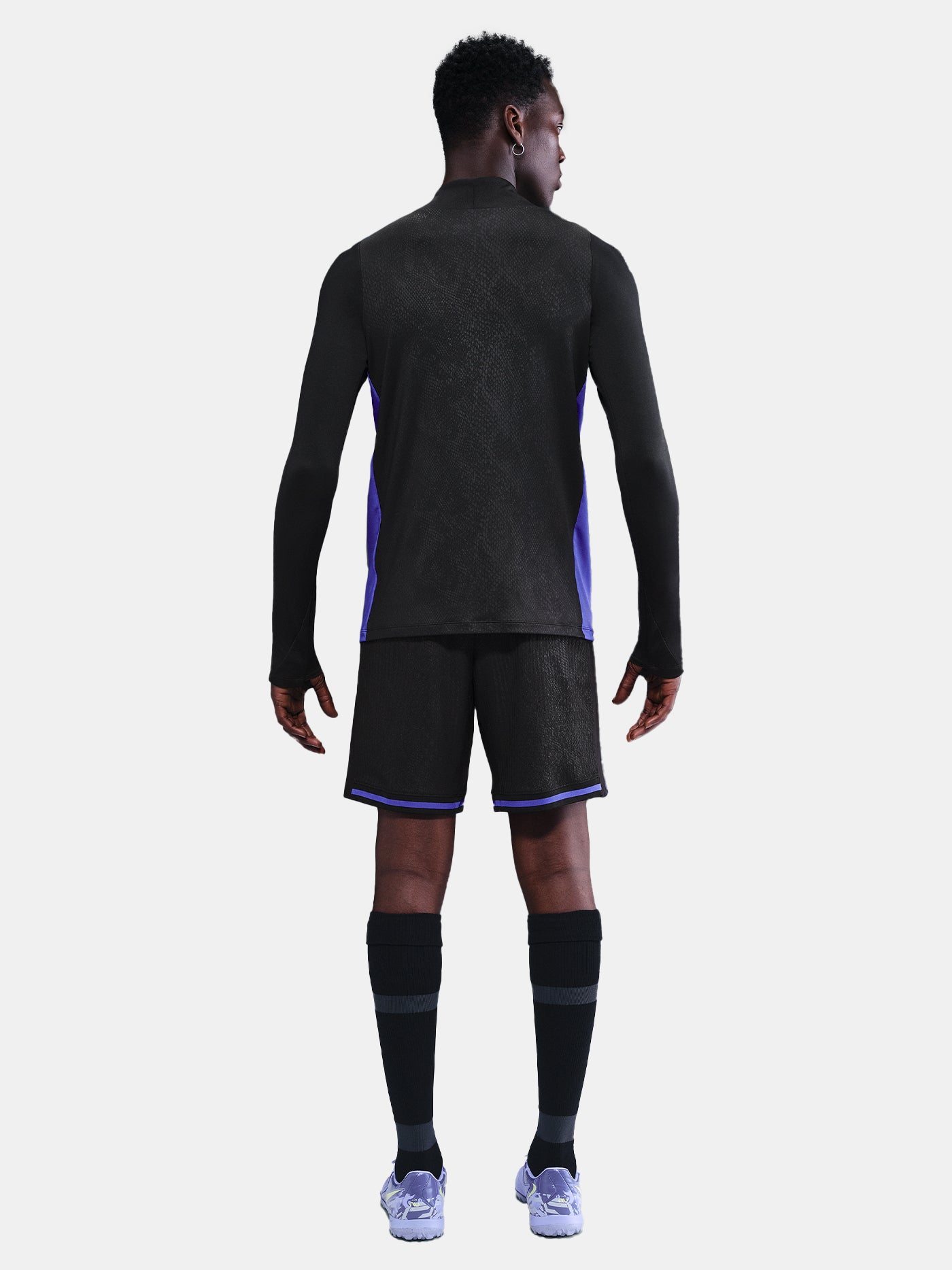 Black FC Barcelona training top with purple details, including the club crest, Nike logo, and Spotify sponsor logo, worn by a person.