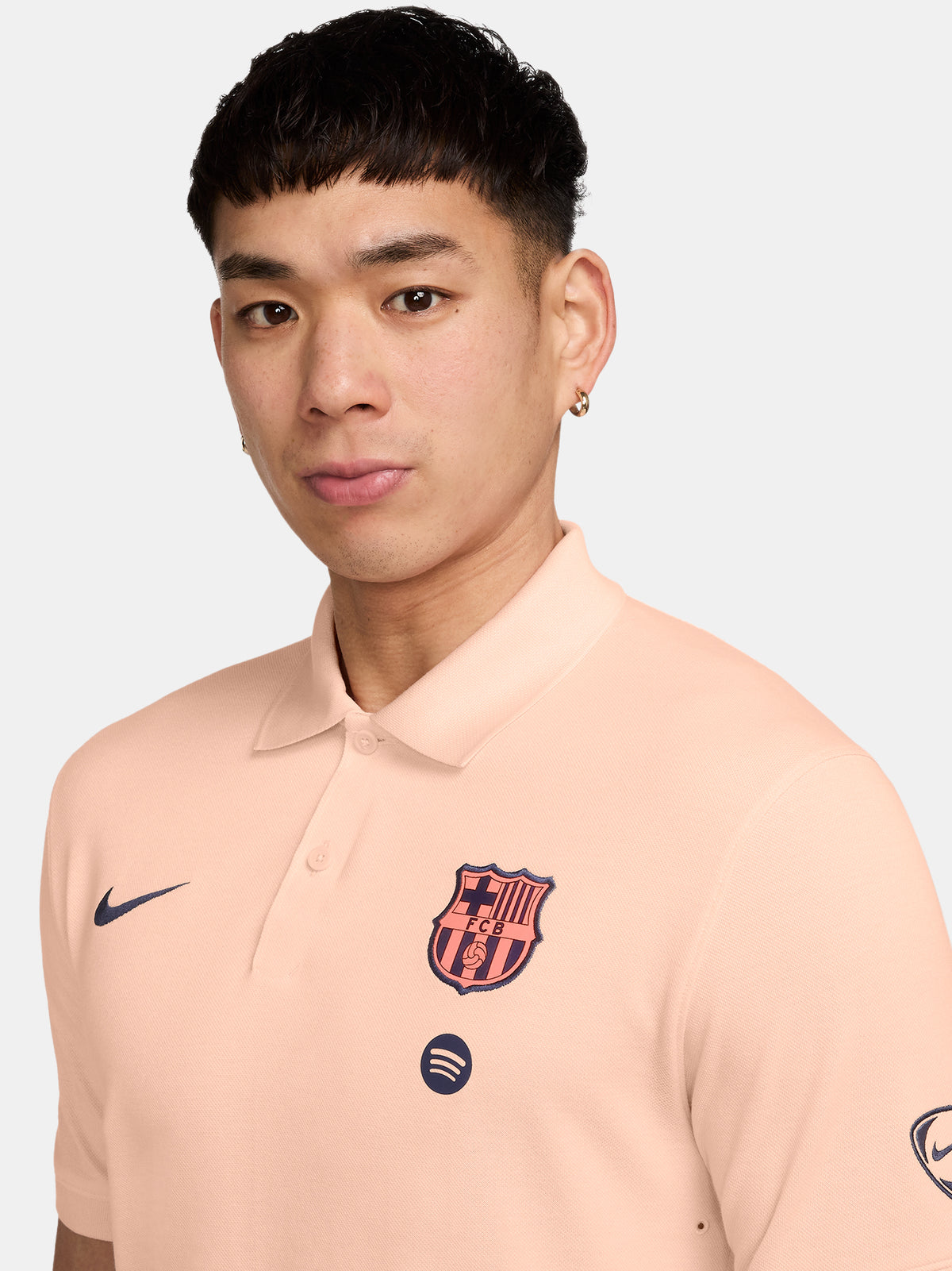 FC Barcelona light peach polo shirt with collar, featuring the club crest and Spotify logo on the chest alongside the Nike swoosh in navy