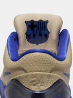 Beige and blue sneaker with FCB logo on a light gray background
