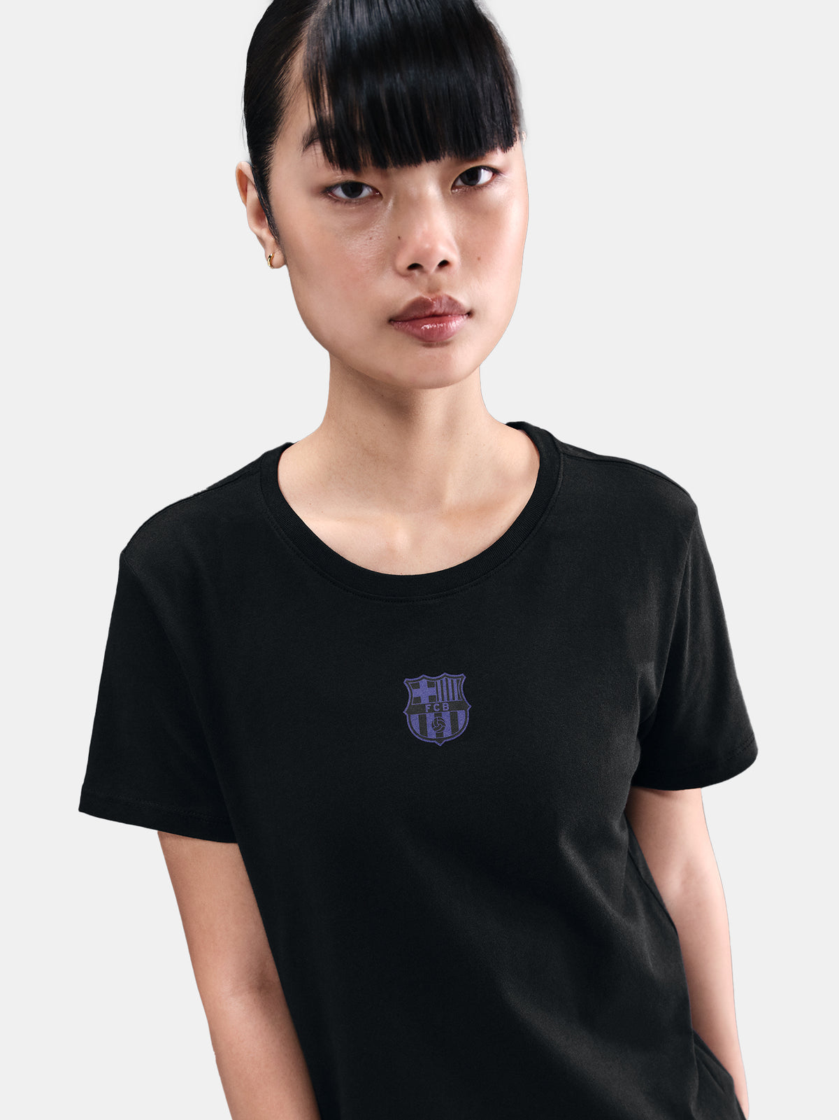 Black FC Barcelona Nike t-shirt with blue Barça crest on the chest, worn casually with blue pants and a black shoulder bag